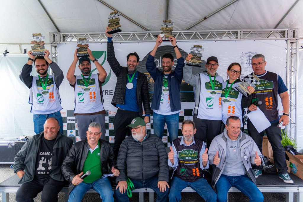 Vencedores do Rally de Carros Elétricos exibem os troféus com os organizadores.