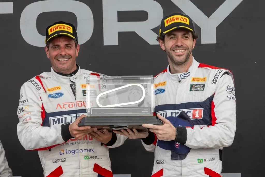 Julio Campos e Alex Seid seguram troféu no pódio apoós conquista em Curvelo (MG), na NASCAR Brasil