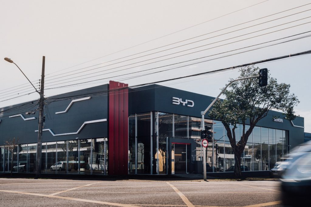 Fachada da concessionária BYD Servopa em Curitiba, com veículo em movimento na rua.